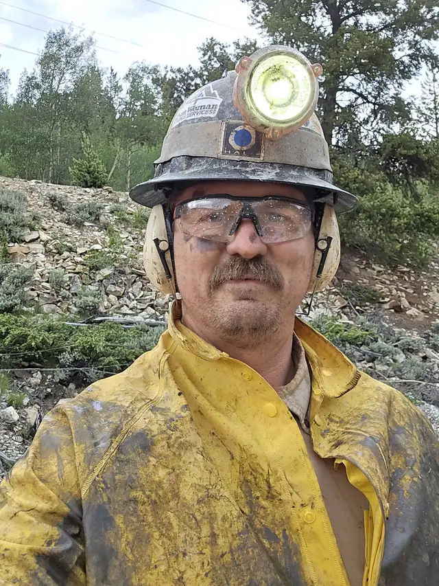 Ben Litsey in yellow rain gear, hard hat, cap lamp, safety glasses and ear muffs