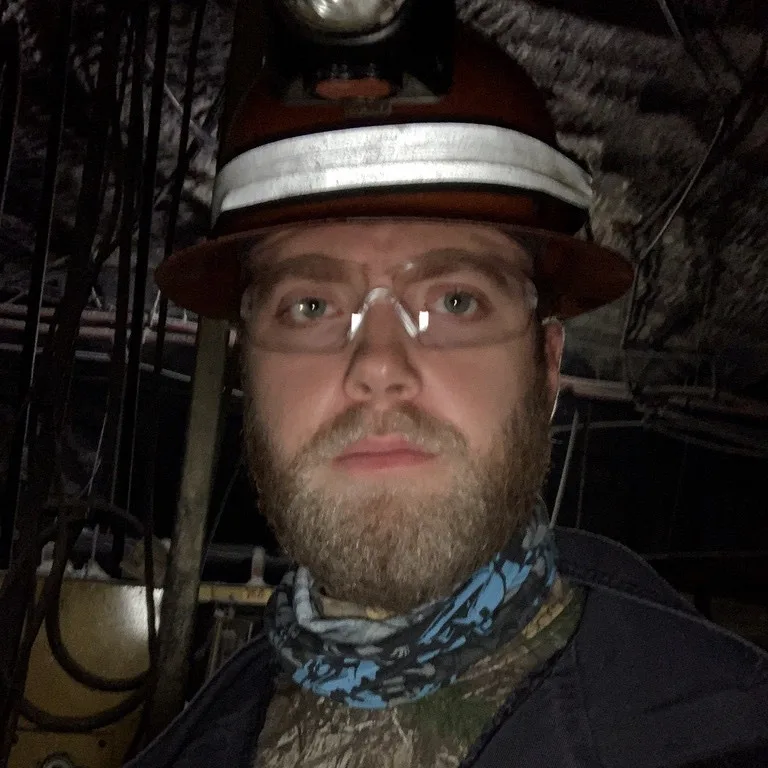 Dan Gauerke underground in a hard hat, cap lamp and safety glasses