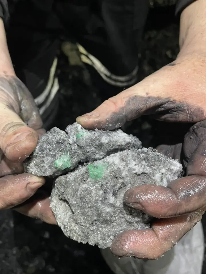 Emerald in host rock, held in a miner's hands